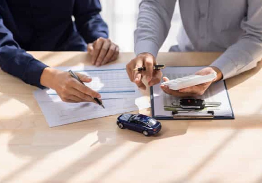 Dealer salesman giving car key to owner. client signing insurance document or rental car lease form agreement contract Insurance car concept.